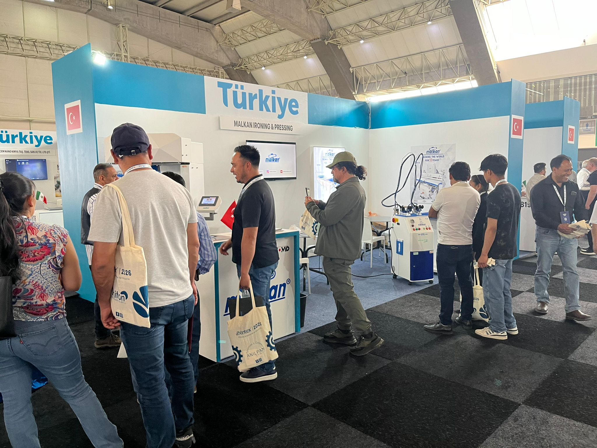 Professional visitors examining the Industry 4.0 ERP integration of Malkan's high-pressure industrial ironing systems